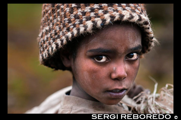 Retrato de un niño junto a las montañas de Simien. Las bellezas de los montes Simien son genuinas y universalmente admiradas, ante ellas solo resta la contemplación. Uno puede preguntarse que fuerzas y poderes sobrenaturales han creado esta maravilla.El parque nacional de las montañas Simien tiene muchas cimas por encima de los 4000 m, siendo Ras Dashen el pico más alto de Etiopía y el cuarto de Africa con 4620 m. Con al menos tres diferentes zonas botánicas, el parque es conocido por su diversa ecología, fauna y flora. Tres de los siete grandes mamíferos endémicos de Etiopía – la cabra Walia, el babuino Gelada y el zorro rojo de los Simien, se encuentran aquí.El parque se sitúa en una región de clima semi-árido, con menos de 600 mm anuales de precipitaciones, distribuidas de octubre a abril. Se distinguen tres tipos de vegetación en función de la altitud. En el nivel inferior, entre 3000 y 3300 metros, la vegetación original de cedros y mañíos ha sido sustituida por cultivos agrícolas, salvo en las zonas más inaccesibles. El nivel intermedio, hasta 4000 metros, también está muy degradado y sólo en escasos enclaves se conservan los bosquetes originales de brezo y salvia. El nivel superior está dominado por praderas semialpinas, salpicadas de afloramientos rocosos y bosquetes de brezos gigantes, que alcanzan hasta siete metros de altura. Conocido como el “techo de Africa” y situado a 120 Km de Gondar, el parque nacional de las montañas Simien fue el primero de los siete lugares herencia de la Humanidad del país en ser designado como tal por la UNESCO. Los visitantes del parque deben estar preparados para la posibilidad de días cálidos y fuerte sol. Los meses de Noviembre y Diciembre son los meses más fríos.