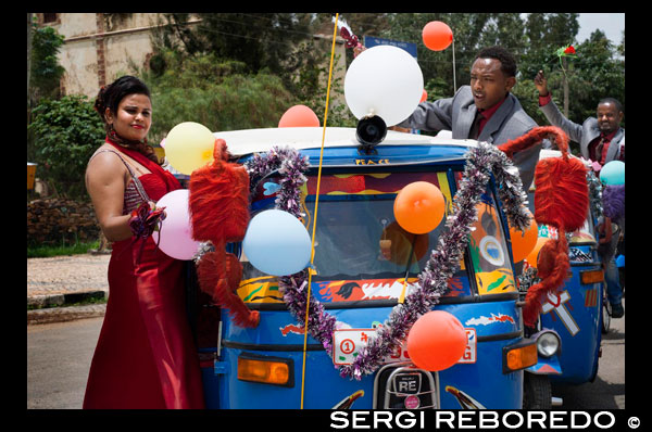 La comitiva nupcial recorre las calles de Axum a bordo de un tuc-tuc festejando que se acaban de casar sus allegados.  AXUM ES LA CIUDAD MÁS ANTIGUA DE ETIOPÍA Y PROBABLEMENTE DEL MUNDO. Cuenta la leyenda que es en esta ciudad creada por los habitantes del puerto de Adulis cuando éste fue destruido, nació Melenik I, hijo del rey Salomón y la Princesa de Saba. De hecho, todavía se conservan las ruinas del Palacio de la Reina de Saba en cuyas cercanías hay un lago en donde supuestamente se bañaba la reina y donde los habitantes de la ciudad recogen agua pues la consideran mágica. También son interesantes los Monolitos de granito conocidos como Estelas que están construidos siguiendo técnicas árabes, el de mayor altura alcanza los 34 metros y todos ellos tienen un significado conmemorativo. Se distingue, además, la Iglesia de Santa María de Zión a cuyo interior no pueden pasar las mujeres ya que la antigua iglesia fue destruida por una reina pagana. En su interior se conserva el Arca de la Alianza que según cuenta la tradición fue traída a este recinto por Menelik I desde la ciudad santa de Jerusalén. Si dispone de tiempo le aconsejamos la visita al Museo de la ciudad. 