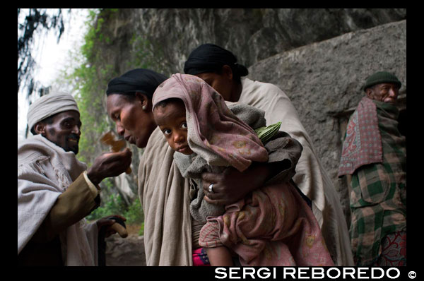 Una dona besa la cuz d'un sacerdot a l'església de Nakuto Lab, als afores de Lalibela. A 2.400 metres d'altitud, en el planell etíop, al nord d'Addis Abeba, es troba aquesta petita localitat monàstica (la segona ciutat d'Etiòpia considerada Santa), coneguda en l'antiguitat com Roha i que, va canviar el seu nom després de ser conquerida al segle XIII pel monarca Gebra Maskal Lalibela, qui la "batejar" com Lalibela. Va ser, per mandat d'aquest rei, quan es va començar la construcció d'aquestes singulars esglésies, singulars pel fet que estan excavades a la terra, fet que les converteix en úniques i que els va merèixer el 1979, el reconeixement com a Patrimoni de la Humanitat per la UNESCO. La ciutat de Lalibela al sud d'Etiòpia és coneguda per les seves dotze esglésies cristianes llaurades a la roca fa 800 anys. La més sorprenent és Bieta Giyorgis, a la imatge, un monumental monòlit de 12 metres d'altura, esculpit intrincadamente a la pedra i amb forma de creu.