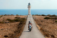 Formentera. Dos motociclistes joves en un llarg camí d'Es Cap de Barbaria far, a Formentera, Illes Balears. Espanya. Barbaria cape formentera carretera del far.