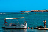 Formentera. Platja Els Pujols a Formentera. Els turistes fan fotos amb el vaixell de pesca tradicional al dia d'estiu. Llaüt.