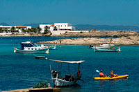Formentera. Playa Els Pujols en Formentera con el barco de pesca tradicional y kayaks en día de verano. Barcos Llaüt.