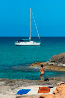 Formentera. Mujer desnuda en la playa de Es Calo, Formentera, el mar Mediterráneo, Islas Baleares, España. Es Caló de Sant Agustí con el barco en la isla de Formentera turquesa mediterráneo.
