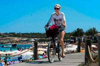 Formentera. Es Pujols, playa, Formentera. Muchacha que monta bicicleta. Vista panorámica, sombrilla, tumbona, el turismo, las vacaciones. España, Islas Baleares, al sur de la isla de Ibiza, la isla de Formentera, la playa de Es Pujols.