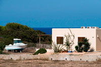 Formentera. Típica casa blanca de Formentera. Es Calo de la playa de San Agustí, Isla Formentera, el mar Mediterráneo, Islas Baleares, España. Es Caló de Sant Agustí con el barco en la isla de Formentera