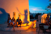 Formentera. Tourists, Girl paying outside of the Church in main square of Sant Francesc Xavier, San Francisco Javier, Formentera, Pityuses, Balearic Islands, Spain, Europe.  