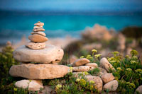 Formentera. Ses Illetes Platja, Illes Balears, Formentera, Espanya. Retroiluminació de la posta de sol amb pedres de diferents formes. "El Diluvi" ("La Riuada"), un espai únic construït amb pedres per part de la Johannes Schultz alemany.