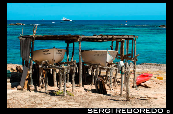 Playa Els Pujols en Formentera con el barco de pesca tradicional en el día de verano. Llaüt. Está separada de la zona residencial por un paseo peatonal donde los puestos de souvenirs hippy se presenten en la noche. Playa de Es Pujols está formada por tramos de arena y tramos de rocas de baja altitud, donde se pueden encontrar cabañas de pescadores, donde guardan sus barcos.