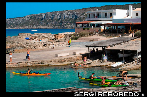 Kayak in Es Calo de San Agusti beach, Formentera Island, Mediterranean sea, Balearic Islands, Spain. Can Rafalet Restaurant. Es Calo de San Agusti with boat in Formentera island turquoise mediterranean.  Small refuge for fishermen, where you can taste the sea in a maritime environment. The beach is small and the La Mola cliffs can be seen on the right. We recommend visiting the area and the nearby restaurants.