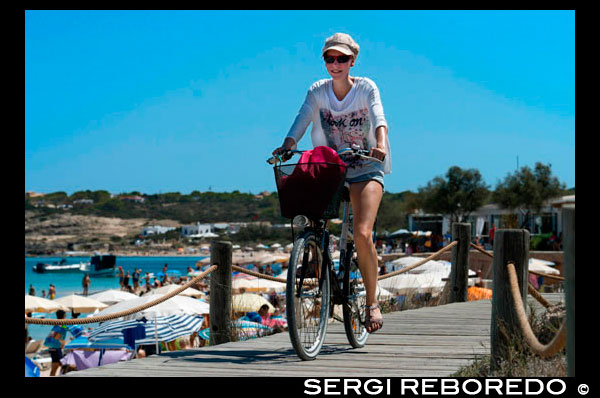 Es Pujols, playa, Formentera. Muchacha que monta bicicleta. Vista panorámica, sombrilla, tumbona, el turismo, las vacaciones. España, Islas Baleares, al sur de la isla de Ibiza, la isla de Formentera, la playa de Es Pujols. España; Formentera; Es Pujols; playa; Pujols; la gente fondo; balear; Islas Baleares; playa; playa de Es Pujols; Chica; mujer; bicicleta; moto; atractivo; gira; eco; ecología; mar; activo; europa; isla de Formentera; vista general; baño; sol; islas; litoral; mar Mediterráneo; sombrilla; personas; mar; al sur; España; turismo; turismo; vacaciones; isla; balear; Baleares; fondo; balear; playa; hermosa; azul; calmar; costa; europa; exótico; formentera; vacaciones; idílico; isla; islote; hito; paisaje; llevant; mediterráneo; la naturaleza; océano; al aire libre; el paraíso; lugares; la reflexión; arena; escénica; mar; paisaje marino; superficial; orilla; cielo; España; verano; luz del sol; soleado; tanga; turismo; turístico; transparente; viajar; trópico; tropical; turquesa; vacaciones; agua; olas; ondulado; húmeda; blanco; atrraction; destino; Europa; Europea; vacaciones; viajar; islas; mediterráneo; fotos; colocar; Español; sol; turismo; turístico; vacaciones; vista; Baleares; hermosa; belleza; el paraíso; divertido; feliz; costera; paradisíaca; popular