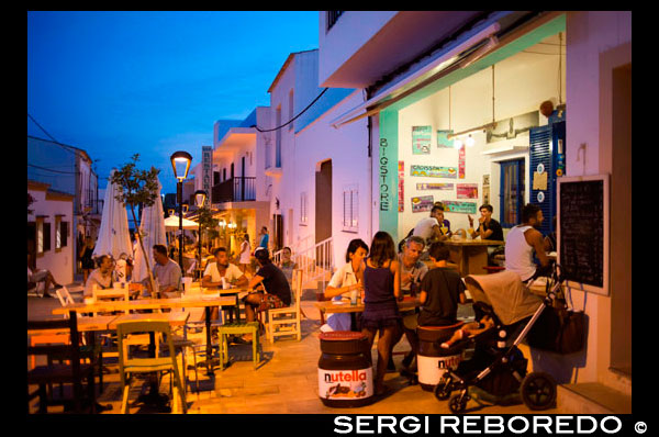 Los turistas, Big tienda, bar y restaurante en la calle Isidor Macabich de Sant Francesc Xavier, San Francisco Javier, Formentera, Pitiusas, Islas Baleares, España, Europa. Al lado de la Plaza de la Constitución. España; Formentera; isla; balear; Sant Francesc; Xavier; San Francisco; Francisco; Javier; principal; la puesta del sol; cuadrado; central; típica; blanco; casas; casa; bar; bares; Rentaurant; restaurantes; turistas; agradable; Ayuntamiento; día; la luz del día; durante el día; durante; europa; europeo; exterior; exteriores; formentera; vacaciones; días de fiesta; isla; islas; javier; viaje; al aire libre; foto; fotos; Pitiusas; colocar; lugares; san; sant; tiro; disparos; pequeña; al sur; el sur; España; Español; cuadrado; cuadrados; turismo; turistas; la ciudad; pueblos; viajar; viajar; viaja; viaje; viajes; vacaciones; vacaciones; pueblo; pueblos; Baleares; atrraction; destino; Europa; Europea; vacaciones; viajar; islas; mediterráneo; fotos; colocar; Español; sol; turismo; turístico; vacaciones; vista; Baleares; hermosa; belleza; el paraíso; divertido; feliz; costera; paradisíaca; popular