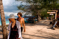 Unos turistas caminan por un paseo que discurre por el lateral de la zona Este de la isla, lugar donde se aglutinan la mayoría de hoteles. Gili Meno.  