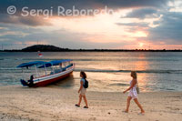 Dues dones passegen per la sorra de la platja de la zona Oest de l'illa, prop de l'embarcador del Bounty Resort. Gili Meno.
