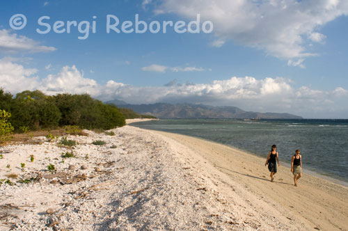 Dues dones passegen per la sorra de la platja de la zona Oest de l'illa, prop de l'embarcador del Bounty Resort. Gili Meno. Únicament el cloqueig de les gallines i, al lluny, el xiulet intermitent dels ocells. El temps passa molt a poc a poc en Gili Meno. De vegades no sembla que ho faci, en realitat.