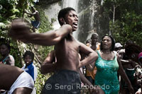 El festival de vudú de Saut d'Eau se celebra cada año el 16 de Julio coincidiendo con el día en el que en 1847 apareció una visión de la Virgen Maria. Miles de devotos llegados de todos los lugares de Haiti se bañan en estas aguas para purificarse o pra perdirle al Gran Maestro que convierta en realidad sus sueños. El vudú es la religión mayoritaria de Haiti. Los adeptos necesitan ser poseidos por un espiritu Iwa para poder comunicarse con el Gran Met, ya que este se encuetra muy alejado del plano físico. En la fotografía una adepta se encuentra poseida por el gran Iwa. Grita y sus movimientos son convulsos. Una vez en la cascada, los creyentes pueden pasar horas en el agua, a veces en trance. Con sus brazos elevados al cielo, bajo la caída del agua o acostados en los cursos de agua que corren sobre grandes rocas, toman "el baño de la suerte".  Según la tradición, los fieles dejan como ofrenda una prenda de ropa o un objeto personal. La fiesta de la Virgen de "Mont-Carmel" atrae también a miles de jóvenes en busca de placeres, lo cual lleva a las ONG a multiplicar las distribuciones de preservativos en su lucha contra el sida.