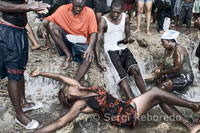 Una mujer en trance se baña en una de las pozas de Saut d’eau para conectar con un Iwa. Exiten infinidad de Iwas, como por ejemplo Damballah que normalmente se pinta con una serpiente que se muerde la cola. El señor del cielo y gran zombi representa el caos y el orden en la creación del mundo. Tiene la dualidad de poder ser muerte y renacimiento, enfermedad y salud, y masculino y femenino. El equivalente que tiene en el cristianismo es San Pedro y las ofrendas que se le da suelen ser gallinas blancas, huevos, arroz y leche.