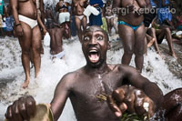 Un hombre en trance en una de las pozas de Saut d’eau. El festival de vudú de Saut d'Eau se celebra cada año el 16 de Julio coincidiendo con el día en el que en 1847 apareció una visión de la Virgen Maria. Miles de devotos llegados de todos los lugares de Haiti se bañan en estas aguas para purificarse o pra perdirle al Gran Maestro que convierta en realidad sus sueños. El vudú es la religión mayoritaria de Haiti. Los adeptos necesitan ser poseidos por un espiritu Iwa para poder comunicarse con el Gran Met, ya que este se encuetra muy alejado del plano físico. En la fotografía un adepto se encuentra poseido por el gran Iwa. Grita y sus movimientos son convulsos. El trance, momento en el que los espíritus Iwa se introducen en el cuerpo de los adeptos. Desde primeras horas , los fieles haitianos comienzan a acudir a los campos santos cargados de café, «klerec» (bebida autóctona de fuerte graduación alcohólica) y todo tipo de alimentos para ofrecer a los espíritus. El vudú, aunque no de una forma siempre visible, está presente en todos los ámbitos de la vida del país y hasta los colores azul y rojo de la bandera nacional representan a Ogou, espíritu de la guerra, el fuego y el cosmos. Previamente el rito exige que estas mujeres consagradas a la religión vudú purifiquen sus cuerpos y limpien sus órganos sexuales con el líquido que extraen de una botella repleta de hierbas antes de recibir al espíritu. Violentos movimientos, bailes y una continúa ingesta de alcohol caracterizan los momentos en los que las sacerdotisas del vudú prestan sus cuerpos a los espíritus de los muertos. La multitud, que en todo momento permanece alrededor de los sacerdotes, anima con cantos y gritos a éstos en sus contactos con el otro mundo. Otra de las características esenciales de esta religión de origen africano es su profunda fluidez, en parte porque no tiene liturgia ni teología escrita y en parte por las diversas influencias que ha tenido de otras religiones. Vudú en África: Christian enojos demonización seguidores  Sacerdotes de Benin tratar de disipar las falsas ideas sobre la religión antigua practicada por mitad de la población del país  Pero por el silbido suave de pitones, templo Dah Dangbénon del vudú podría haber sido confundido con un encuentro hippy de la nueva era. Sentados en semicírculo sobre el deshilachado esteras de rafia, los devotos escucharon con entusiasmo como el sumo sacerdote habló largo y tendido sobre la unidad con el cosmos.  "No puede haber equilibrio sin respetar las leyes universales de la naturaleza, y nuestro conocimiento ancestral y tradiciones", dijo Dangbénon, un hombre de cabello plateado que las uñas estaban pintadas de un rosa brillante improbable.  Él puso los ojos en exasperación al explicar cómo una fe que expresamente prohibía matar a otro ser humano había sido "fetichizada" por terceros. "El vudú no es sobre el uso de los hechizos mágicos para maldecir a sus enemigos", dijo Dangbénon, cuyo clan durante generaciones ha supervisado este templo dedicado a pitones. "Si opta por manipular a la naturaleza hacer daño a tu prójimo, no es vudú que daña a su prójimo, eres tú."  Al igual que su primo nigeriano, juju, el vudú se originó en antiguo reino de Benin Dahomey. Hoy en día la tradición basada en la naturaleza está tan entretejida con la vida cotidiana que raya en lo banal en Benin. Los templos se ranurada entre restaurantes zumbido y farmacias, pasa por alto fácilmente. Tiny talismanes esculpidos oscilar decorativamente en los portales donde los pollos rayar y dardo niños ruidosamente alrededor. Ancianos cotilleo en los bares de carretera derramar el primer trago de cerveza cada uno para honrar a los espíritus.