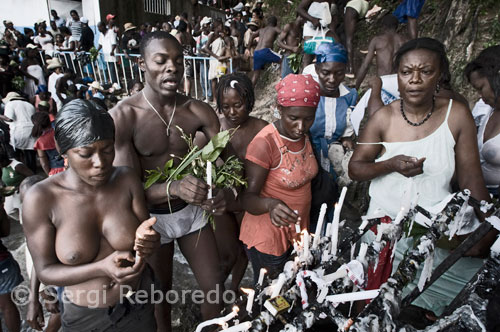 Cerca de la cascada, hombres y mujeres venden velas, cordones azules y blancos que representan a los loas e imágenes de la Virgen de los Milagros. Los tambores tocan ritmos sincopados, y algunas personas entran en trance, hablando en voz alta y moviéndose frenéticamente. Más allá de los estereotipos, que describen al Vudú como pura magia negra, rituales con muñecas, sacrificios de animales y muertos vivientes, ésta es básicamente una religión pacífica, en la que los ritos constituyen una experiencia mística para los iniciados. Existe también el Vudú Congo, que se distingue por el uso de maldiciones, males de ojo y "polvos maléficos". Más de 60 millones de personas practican el Vudú en todo el mundo. Los rasgos de esta religión proceden de la cultura animista de un pueblo africano, los yorubas, provenientes de Nigeria, Benín y Togo.