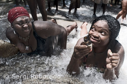 Dos devotas comparten el baño de la suerte haciendolo más llevadero si cabe con un botellín de Ron Barbancourt, el ron haitiano por excelencia. El baño se realiza en una serie de charcas poco profundas y rodeadas de vegetación, cuyas aguas creen que son sagradas. En los alrededores se encienden velas y susurran ruegos a los adeptos que han tenido la suerte de ser poseidos por el mismisimo Erzuli.