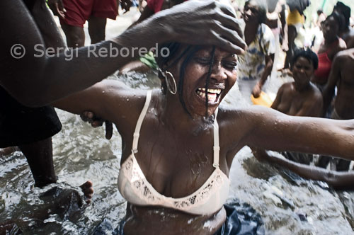 El festival de vudú de Saut d'Eau se celebra cada any el 16 de juliol coincidint amb el dia en què el 1847 va aparèixer una visió de la Verge Maria. Milers de devots arribats de tots els llocs de Haiti es banyen en aquestes aigües per purificar o compra perdre al Gran Mestre que converteixi en realitat els seus somnis. El vudú és la religió majoritària de Haiti. Els adeptes necessiten ser posseïts per un esperit Iwa per poder comunicar-se amb el Gran Met, ja que aquest es encuetra molt allunyat del pla físic. A la fotografia una de les assistents es encuetra posseïda pel gran Iwa. Hi ha un gran nombre de Iwas, cadascun amb característiques diferents que abasten nombres sagrats, colors, dies, aliments cerimonials i objectes rituals. Una dona entra en trànsit. Si bé el 'vudú' és bàsicament una religió pacífica, basada en esperits i forces de la natura, a les quals es convoquen en cerimònies en les que els seus participants arriben al èxtasi místic, es realitzen curacions i es sacrifiquen galls, la majoria dels occidentals associa el vudú amb la minoritària, però practicada, vessant malèfica o 'Petro' (també anomenada 'Congo'). Aquesta màgia negra és emprada per fer el mal a través de malediccions, mals d'ull, creació de zombis-morts ressuscitats pels 'Bokor' o mags malèfics amb dolents intencions-i orgies sexuals. Si hi ha una paraula que ve a la ment quan es parla d'Haití, aquesta és "vudú". Tot i que la majoria de la població es reparteix entre catòlics i protestants, els haitians no tenen problemes en compaginar i fins i tot assimilar aquestes creences amb el vudú, en un exercici de sincretisme. Encara que es adora a un sol déu, Bondy, són també molt poderosos altres éssers, com els 'lloances'-Legba, Kalfu, Papa GEDE o Erzuli-esperits familiars i de les forces de l'univers, i els 'morts'. Aquests, comandats pel Baró Samedi, vestit com un empresari de pompes fúnebres, es divideixen en dos grups: els adorats, benefactors, i els abandonats, perillosos per als vius.