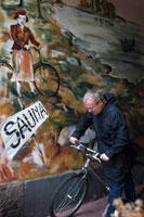 Helsinki. A customer with a bicycle at Arla Sauna door. The Sauna Arla is one of the few remaining old public saunas in the city, at the corner of an apartment block in the district of Kallio now understand my surprise when, during my visit to the sauna Arla, the first two sounds we hear were open cans of beer and loud jokes by a group of rough-looking men. I found this fascinating cultural difference became even more interesting when I witnessed Finns usually rather shy, squeezing the buttocks themselves-to-buttock in the top row of the sauna. The interior of the sauna - and certainly only a sauna, not a lot of different temperature saunas - is also very different from anything I've found in Germany before: is courageous, no ill equipped and wall tiles the plaster peeling off the roof.