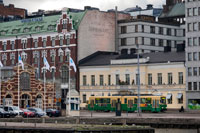 Helsinki. Vistas genrales de la ciudad con el tranvía y el mercado de fondo en calle Eteläranta.  Visita al mercado. Junto al mercado exterior del puerto, encontrarás el mercado cubierto. Es un buen lugar para probar el pescado local o para comprar embutidos de reno.  Plaza del Mercado Viejo Esta zona de la ciudad de Helsinki, es quizá la más bulliciosa y aglomerada de la ciudad. Las razones son evidentes, por un lado es el nudo del que parten las calles comerciales más importantes, también es punto de partida de los feries que llevan a Suomennlina y los barcos que realizan paseos por la costa. Aparte la rodean monumentos como la Catedral, la Iglesia Uspenski, el Palacio Presidencial y la Corte Suprema, y es, en sí centro del pequeño comercio y de los puestos de comida, artesanías y frutas de temporada que se realizan en verano, que se convierten en artesanía y repostería navideña en Diciembre. 