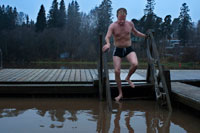 A man cools outside the private Sauna Pikkukoski north of the city of Helsinki, Vanhankaupunginselkä lakeside, near the town of Oulunkylä Aggelby. A defined area of the lake has heating in water so that it never freezes in winter and people can swim.