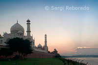 The Taj Mahal complex is bounded on three sides by crenellated red sandstone walls; with the river-facing side left open. Taj Mahal is regarded as one of the eight wonders of the world; and some Western historians have noted that its architectural beauty has never been surpassed. The Taj is the most beautiful monument built by the Mughals; the Muslim rulers of India. Taj Mahal is built entirely of white marble. Its stunning architectural beauty is beyond adequate description; particularly at dawn and sunset. The Taj seems to glow in the light of the full moon. On a foggy morning; the visitors experience the Taj as if suspended when viewed from across the Jamuna river. Taj Mahal was built by a Muslim; Emperor Shah Jahan (died 1666 C.E.) in the memory of his dear wife and queen Mumtaz Mahal at Agra; India. It is an "elegy in marble" or some say an expression of a "dream." Taj Mahal (meaning Crown Palace) is a Mausoleum that houses the grave of queen Mumtaz Mahal at the lower chamber. The grave of Shah Jahan was added to it later. The queen’s real name was Arjumand Banu. In the tradition of the Mughals; important ladies of the royal family were given another name at their marriage or at some other significant event in their lives; and that new name was commonly used by the public. Shah Jahan's real name was Shahab-ud-din; and he was known as Prince Khurram before ascending to the throne in 1628. Taj Mahal was constructed over a period of twenty-two years; employing twenty thousand workers. It was completed in 1648 C.E. at a cost of 32 Million Rupees. The construction documents show that its master architect was Ustad ‘Isa; the renowned Islamic architect of his time. The documents contain names of those employed and the inventory of construction materials and their origin. Expert craftsmen from Delhi; Qannauj; Lahore; and Multan were employed. In addition; many renowned Muslim craftsmen from Baghdad; Shiraz and Bukhara worked on many specialized tasks.