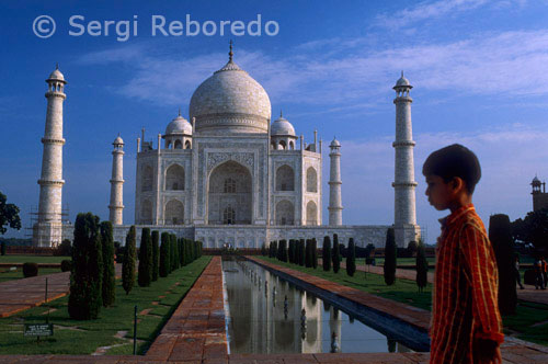 INDIA CRUZANDO EL RIO GANGES vista Taj Mahal delante. Construido en la década de 1630 temprano por el emperador mogol Shah Jahan en homenaje a su segunda esposa, Mumtaz Mahal, el Taj Mahal se presenta como una de las bellezas más emblemáticos de la India. Su simetría precisa e impecable detalle está decorado con caligrafía del Corán y con tallas de flores con incrustaciones de piedras preciosas, hacen de esta estructura de mármol blanco de las piezas más impresionantes del mundo de la arquitectura. Situado junto al río Yamuna, el Taj tomó 22 años y 20; 000 trabajadores para completar. Contiene una tumba (por Mumtaz) y una mezquita, así como jardines, pasarelas, y fuentes. La estructura principal está rodeada por cuatro minaretes, que fueron construidos a inclinarse ligeramente hacia afuera de modo que un terremoto no les haría caer en el palacio.