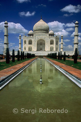 INDIA CROSSING THE RIVER GANGES Taj mahal front view. The Taj Mahal represents the finest and most sophisticated example of Mughal architecture. Its origins lie in the moving circumstances of its commission and the culture and history of an Islamic Mughal empire's rule of large parts of India.The distraught Mughal Emperor Shah Jahan commissioned the mausoleum upon the death of his favourite wife; Mumtaz Mahal. Today it is one of the most famous and recognisable buildings in the world and while the white domed marble mausoleum is the most familiar part of the monument; the Taj Mahal is an extensive complex of buildings and gardens that extends over 22.44 Hectares and includes subsidiary tombs; waterworks infrastructure; the small town of 'Taj Ganji' and a 'moonlight garden' to the north of the river. Construction began in 1632 AD; (1041 AH); on the south bank of the River Yamuna in Agra; and was substantially complete by 1648 AD (1058 AH). The design was conceived as both an earthly replica of the house of Mumtaz in paradise and an instrument of propaganda for the emperor.