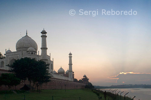 ÍNDIA CREUANT EL RIU GANGES El complex del Taj Mahal està limitada a tres costats per parets emmerletades de pedra arenisca vermella, amb el costat del riu, mirant cap a l'esquerra oberta. Taj Mahal és considerat com una de les vuit meravelles del món, i alguns historiadors occidentals han assenyalat que la seva bellesa arquitectònica no ha estat superat. El Taj és el monument més bell construït pels mogols, els governants musulmans de l'Índia. Taj Mahal està construït enterament de marbre blanc. La seva bellesa arquitectònica està més enllà d'una descripció adequada, sobretot a l'alba i al capvespre. El Taj sembla brillar a la llum de la lluna plena. En un matí de boira, els visitants experimentar el Taj com si estigués suspès quan es veu des de l'altre costat del riu Jamuna. El Taj Mahal va ser construït per un musulmà, l'emperador Shah Jahan (mort el 1666 dC) a la memòria de la seva estimada esposa i la reina Mumtaz Mahal a Agra, Índia. Es tracta d'una "elegia en marbre" o alguns diuen que l'expressió d'un "somni". Taj Mahal (és a dir, Palau de la Corona) és un mausoleu que acull la tomba de la reina Mumtaz Mahal a la cambra baixa. La tomba de Shah Jahan es va afegir més tard. nom real de la reina va ser Arjumand Banu. En la tradició dels mogols, dames importants de la família reial se'ls va donar un altre nom en el seu matrimoni o en algun altre esdeveniment important en les seves vides, i que el nou nom va ser utilitzat comunament pel públic. el veritable nom de Shah Jahan va ser Shahab-ud-Din, i era conegut com el Príncep Khurram abans d'ascendir al tron en 1628. El Taj Mahal va ser construït en un període de vint-i anys, que dóna feina vint mil treballadors. Va ser acabat en 1648 la CE a un cost de 32 milions de rupies. Els documents de construcció mostren que el seu arquitecte principal va ser Ustad Isa ", el reconegut arquitecte islàmica del seu temps. Els documents contenen noms dels empleats i l'inventari de materials de construcció i el seu origen. artesans experts de Delhi; Qannauj, Lahore, Multan i van ser emprats. A més, molts famosos artesans musulmans de Bagdad, Shiraz i Bujara treballat en moltes tasques especialitzades.