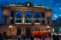 Edificio del gran teatro convertido hoy en día en Opera Nacional de Montpellier en la Place de la Comédie.  Dinámica Occitana. En el siglo XVIII, los muros de la ciudad medieval fueron reemplazados por avenidas y plazas. El centro neurálgico de Montpellier está en la Plaza de la Comédie, con la fuente de Las Tres Gracias y el edificio parisino de la Opéra-Comédie. Para llegar al barrio más moderno de Antigone, hay que atravesar el Poligone, la zona comercial. Al final del Medioevo, Montpellier estaba encerrada por fortificaciones y comenzaba a asfixiarse. A nadie le importaba pero –casi como un símbolo– crecían pinos desde una de las torres, bautizada La Tour des Pins. En esa época, el doctor Nostradamus, recibido en la universidad de esa misma ciudad, curaba con plantas medicinales, ayudado por la astrología. En una de sus tantas predicciones, habría dicho que Montpellier desaparecería cuando los pinos de la torre, ya viejos, se cayeran. Sin embargo, tiempo después, el doctor murió; y los pinos, cuyas raíces arruinaban el edificio, fueron reemplazados por cipreses. Es por eso que, a pesar de Nostradamus, Montpellier –floreciente capital de la región de Languedoc-Roussillon– sigue en pie, en el sur de Francia, a tres horas veinte de París en el tren de alta velocidad. Los automóviles están prohibidos en el Ecusson, el centro medieval de la ciudad, uno de los espacios peatonales más grandes de Europa. En las calles laberínticas, el oído urbano trata de adaptarse al silencio. Y la promiscuidad de estos espacios medievales, con sus hábitos contemporáneos, aumenta el desconcierto. Una soprano ensaya una ópera de Verdi, el sonido de una batería sale de un sótano protegido, alguien duerme con fondo de Chopin. Con el paso del tiempo, el Ecusson vivió transformaciones arquitectónicas que el tejido medieval incorporó sin violencia. Una antigüedad reciclada, con edificios que parecen caerse a pedazos: parte del encanto. Las puertas de entrada, de un metro de altura, están siempre abiertas. Las escaleras caracol son angostas y no están iluminadas. Los alquileres, aquí, son los más caros.