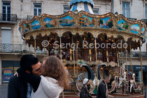 Una pareja se besa junto a una noria situada en uno de los extremos de la Plaza de la Comedia. Alrededor de la Place de la Comedie, centro neurálgico de la ciudad con numerosas terrazas y cafés, se pueden ver actuaciones de músicos y artistas, además sus festivales contribuyen a su animada vida cultural y artística. Otras ventajas de esta ciudad son su clima mediterráneo, su cercanía y buena comunicación con España y su cercanía con los Pirineos y la famosa región de la Camargue, con sus largas playas de arena y sus lagos con colonias de flamingos salvajes, ideal para las personas que les gusta la naturaleza y las excursiones al aire libre. 