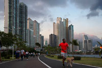 Hombre que corre con el perro en la Avenida Balboa carretera rascacielos malecón nuevo. Skyline, Ciudad de Panamá, Panamá, América Central. Cinta Costera Océano Cinta Costera del Pacífico Bahía de Panamá malecón parque lineal rascacielos moderno. Cinta Costera (Cinta Costera), Ciudad de Panamá, Panamá. Ciudad de Panamá es una ciudad en América Central, donde la congestión ha alcanzado un punto crítico. La ciudad está pasando por un período sin precedentes de estabilidad y las inversiones y hay gran cantidad de fondos públicos para proyectos de mejora de la infraestructura.