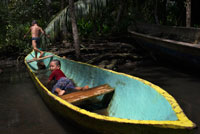 Kids play in one of the local boats used by the Ngobe Indians as their main form of transport, sheltered under a makeshift lean-to. Channel to entrance at The Ngobe Bugle Indian Village Of Salt Creek Near Bocas Del Toro Panama. Salt Creek (in Spanish: Quebrada Sal) is a Ngöbe Buglé village located on the southeastern end of Bastimentos island, in the Bocas del Toro Archipelago, Province and District of Panama.