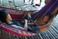 Men and his child doing a siesta in a  hammock in the village of the Native Indian Embera Tribe, Embera Village, Panama. Panama Embera people Indian Village Indigenous Indio indios natives Native americans locals local Parque National Chagres. Embera Drua. Embera Drua is located on the Upper Chagres River. A dam built on the river in 1924 produced Lake Alajuela, the main water supply to the Panama Canal. The village is four miles upriver from the lake, and encircled by a 129.000 hectare National Park of primary tropical rainforest.