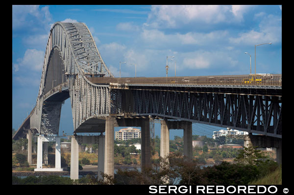 Puente de las Americas, Bridge of the Americas, Thatcher Ferry Bridge, Republic of Panama. The Bridge of the Americas (Spanish: Puente de las Américas; originally known as the Thatcher Ferry Bridge) is a road bridge in Panama, which spans the Pacific entrance to the Panama Canal. Completed in 1962, at a cost of US$20 million, it was the only non-swinging bridge (there are two other bridges, one at the Miraflores locks and one at the Gatun locks) connecting the north and south American land masses until the opening of the Centennial Bridge in 2004. The bridge was designed by Sverdrup & Parcel.  The Bridge of the Americas crosses the Pacific approach to the Panama Canal at Balboa, near Panama City. It was built between 1959 and 1962 by the United States at a cost of 20 million U.S. dollars. From its completion in 1962 until the opening of the Centennial Bridge in 2004, the Bridge of the Americas was a key part of the Pan-American Highway. The Bridge of the Americas greatly increased road traffic capacity across the canal. There are two earlier bridges which cross the canal, but they use moveable designs and have limited traffic capacity. The earlier spans include a small swinging road bridge (built into the lock structure at Gatún) and a swinging road/rail bridge (constructed in 1942 at Miraflores.) The Centennial Bridge was constructed to eliminate this bottleneck and reduce traffic congestion on the Bridge of the Americas.  The bridge is a cantilever design where the suspended span is a tied arch. The bridge has a total length of 1,654 m (5,425 ft) in 14 spans, abutment to abutment. The main span measures 344 m (1,128 ft) and the tied arch (the center part of the main span) is 259 m (850 ft). The highest point of the bridge is 117 m (384 ft) above mean sea level; the clearance under the main span is 61.3 m (201 ft) at high tide. Ships must cross under this bridge when traversing the canal, and are subject to this height restriction. (The Centennial Bridge is also a fixed obstacle, but its clearance is much higher: 80.0 m (262 ft)).