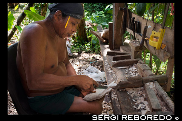 A men of The Ngobe Bugle Indian Village Of Salt Creek Near Bocas Del Toro Panama do wood souvenirs. Salt Creek (in Spanish: Quebrada Sal) is a Ngöbe Buglé village located on the southeastern end of Bastimentos island, in the Bocas del Toro Archipelago, Province and District of Panama.  The community consists of about 60 houses, an elementary school, handcrafts and general stores. The villagers depend mostly on their canoes for fishing and transportation although the village is slowly developing together with the whole archipelago.  Between the Caribbean Sea, with its mangroves, coral reefs, and paradisiacal islands, and the dense humid tropical forest of Bastimentos Island, lies the Ngobe community known as Salt Creek (Quebrada Sal).  Here, the local organization ALIATUR (Salt Creek Tourism Alliance) has created a project so that visitors to the Bocas del Toro Archipelago can get to know the culture of this indigenous community, its artisan crafts, its dances, and its stories.  Actions taken to promote environmental or social sustainability Four hiking trails in the surrounding forests allow the tourist to appreciate the rich fauna and flora of the region. Lodging and typical local food are offered for whoever wishes to visit for one or more days in the community.  In case this isn´t enough, the community´s proximity to the Bastimentos National Marine Park allows tourists to pay a quick visit to the marvelous Zapatilla Cays and to enjoy its beaches, coral reefs, and trail.