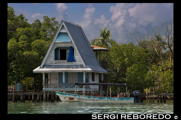 Casa sobre pilotes sobre el agua con paneles solares y una densa vegetación tropical en el fondo, Bocas del Toro, el mar Caribe, Panamá. Cabina tropical sobre el mar Caribe, en el archipiélago de Bocas del Toro, Panamá. Este es el momento ideal para visitar estas islas, a viajar en el tiempo y perderse en uno de los cientos de lugares maravillosos que se pueden disfrutar. Es un lugar único para encontrar a ti mismo; su exuberante vegetación tropical, la fauna sólo se encuentra en esta parte del mundo, las oportunidades para el buceo y el esnórquel océano inmejorable Caribe, las posibilidades y oportunidades para una experiencia increíble se mantienen sin consolidar. Con una belleza natural indescriptible y abrumadora, sumado a la gran combinación de razas y etnias, que viven en armonía con la indígena, pueblos Caribe Occidental, latina y extraneros, Bocas del Toro no es sólo un hermoso archipiélago perdido en el tiempo, bendecido por la naturaleza - Bocas del Toro es un ejemplo de convivencia y respeto multicultural para todos. Bienvenido a Bocas del Toro archipiélago ... .you se divertirán y asombrados, tentados más allá de creencias y por cierto el que deseará llevar con usted recuerdos invaluables de un mundo diferente. Disfrute de su vida ... .. Disfrute de Bocas del Toro! Bienvenidos a unas vacaciones inolvidables.