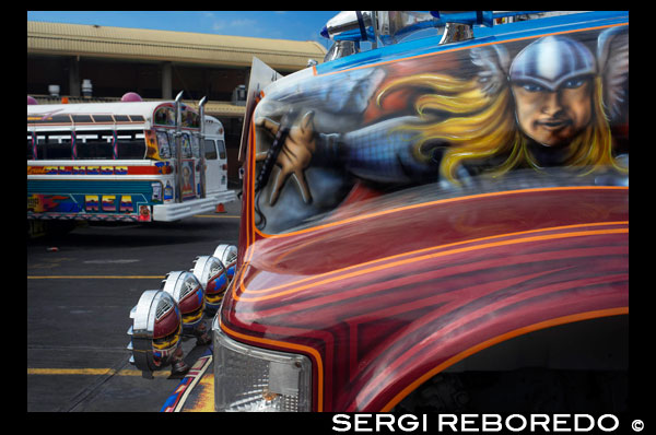 BUS RED DEVIL DIABLO ROJO PAINTED BUS PANAMA CITY REPUBLIC OF PANAMA. Albrok bus station terminal. Panama. Here comes the Diablo Rojo, the Red Devil bus blasting its air horn and fishtailing around a fellow “demon” just in time to claim Irma Betancourt and other morning commuters. Suffice it to say the Red Devils earn their name. “They are crazy,” said Ms. Betancourt, 33, a housekeeper at a downtown hotel, boarding on a main boulevard. “We all know that. All they care about is getting the fare. So many times we have almost hit somebody.”  Wandering around Panama City it’s hard to miss these crazy fuckin buses rolling around the city. Converted school buses are used as inexpensive public transportation. Each bus in the city is individually decorated which makes an interesting catch whenever rolling around. The average cost to ride one of these buses is 25 cents!  “Almost” may make her bus one of the lucky ones, as they are known to have taken more than a few souls for the sake of a pickup.  Her bus on a recent morning is like hundreds of others, a converted, cast-off American school bus ablaze with color, usually heavy on the red.  As if painted by a graffiti artist addicted to action movies and sports, they often boast fanciful, dreamy scenes, including, improbably, a looming Dumbledore from the Harry Potter movies glaring at Ms. Betancourt as she climbs aboard.  Reggaetón, salsa and other bass-heavy music concuss the air, to attract riders to the privately owned buses. Growling mufflers contribute to the soundtrack of the streets. And no self-respecting grille lacks a wild string of Christmas lights.  Typical fare: 25 cents.  “They evolved into the most visually dominant aspect of Panama City,” said Peter Szok, a professor at Texas Christian University in Fort Worth who has studied the buses and the folk art of Panama.  It is a tradition elsewhere in the region as well, in other Panama cities as well as in countries like Suriname, where the buses are adorned with politically tinged portraits of heroes and outlaws. But here, at least, the ride is coming to an end.  The buses, many of them retired from Florida schools, have been the backbone of public transit here for more than four decades, with the tradition of decorating vehicles used for public transportation going back even further. Mr. Szok traces the art form to a desire to reflect Latin music styles and an idealized life.  Panama City, however, is rapidly modernizing, with a towering skyline and sprawling shopping malls that promoters hope will put it on the map as another Singapore.  With that has come a push for order. A subway is being dug. Roadways are being built or planned. The Red Devils, owned and operated by their drivers with no real set schedule, are being phased out in favor of something decidedly more vanilla and benign, a Metro Bus system with generic boxy white vehicles familiar in any cities. The only dash of a color is an orange slash.  “Safe, comfortable, reliable,” is the slogan. There is even a route map.  President Ricardo Martinelli, whose administration has championed the new system, has pointed to the new buses as a sign of progress, blaming the Red Devils for accidents and accusing them of unreliable service.  “They will race from one end of the city to the other, killing people, killing themselves,” he said in a speech in Washington in April. “Yeah, a lot of people were killed.”  But the Metro Buses, too, are drawing complaints, mainly for slow service. The 25-cent fare on most routes is expected to rise to 45 cents next year, and is already drawing grimaces. Some have taken to calling them the Diablos Blancos, the White Devils.  “Hey! The line starts back there,” several people shouted at one crowded downtown Metro Bus stop as their ride finally arrived in a downpour.  “Look at this long line and little bus shelter,” said David Polo, 33, who had been waiting for more than 20 minutes. “The new buses may be safer, but they need more of them.”  Panama’s transportation officials said the Red Devils, numbering about 1,200 in recent years, would be gone by the end of this year, but the plan has been delayed more than once as the new system seeks to hire and train drivers.  As the Red Devils disappear — some of them, in the ultimate twist of fate, converted back to school buses, and others dismantled for scrap or sitting in bus boneyards — something a bit unexpected has emerged.  Sympathy for the Red Devils.  The nostalgia ranges from the tongue in cheek — a “Save the Diablo Rojo” YouTube video purports to mourn the end of tourists’ losing their wallets, among other things, on them — to genuine regrets.  “It is a loss of part of our culture,” said Analida Galindo, a co-director of the Diablo Rosso art gallery in the historic Casco Viejo neighborhood. Yes, the gallery name is a play on the Red Devils’ name.  The gallery sells bus doors painted by one of the more prolific Red Devil artists, Oscar Melgar, for $2,500 (no takers yet).  Mr. Szok said the painters were largely self-taught, many of them the sons of West Indian immigrants, though some in later years had gone to art school. They typically charged $2,000 and up to paint the buses, meaning some are a kaleidoscope of images while, in others, the yellow has been barely painted over, depending on the wherewithal of the driver.  “It was a great tradition that people are going to miss,” said one of the painters, Ramón Enrique Hormi, known as Monchi. “Here it is Christmastime, and what am I going to do? I have nothing.”  Some owners, too, have complained that the $25,000 that the government is offering them in compensation for giving up their buses may sound generous but will not carry them very far.  Several drivers said they could not get jobs with Metro Bus because of their poor driving records, though the new system has hired many Red Devil drivers.  Other drivers said they had long held second jobs and would find other work.  “Everything has to come to an end someday,” one driver, Juan Estanciola, said on a recent day outside his modestly painted bus, which is mostly white with purple trim and bears sayings like “Don’t let my presence mess with your mind.”  He spoke at the door of his bus, which had just collided with a taxi on a rainy afternoon.  “It was his fault,” he said. “He cut in front of me. They don’t know how to drive.”