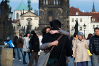 Una pareja se besa apasionadamente en el Puente de Carlos.  El Puente de Carlos (en checo Karl?v most) es el puente más viejo de Praga, y atraviesa el río Moldava de la Ciudad Vieja a la Ciudad Pequeña. Es el segundo puente más antiguo existente en la República Checa. A lo largo de su historia, el Puente de Carlos fue testigo de numerosos acontecimientos, al tiempo que sufrió daños en varias ocasiones. En 1432, una inundación destruyó tres de sus pilares. En 1496, el tercer arco (contando desde el lado de la Ciudad Vieja) se desplomó luego de que uno de los pilares descendiera debido a la erosión en su parte inferior. En esta ocasión, los trabajos de reparación duraron hasta el año 1506. 