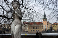 Esculturas junto al Rio Moldava. El río Moldava se abre camino por la mágica ciudad de Praga entre edificios clásicos edificios, y maravillosos puentes que lo cruzan, como el Puente de Carlos y otro más modernos. En la Edad Media este río se utilizaba para transportar madera de los bosques del sur que se destinaba a la construcción. En la historia de la creación de la ciudad, ha tenido un papel esencial. Actualmente, hay aún zonas donde se desciende en balsas, sobre todo en el interior. Los turistas pueden disfrutar de una cena crucero y de las magníficas vistas de la Ciudad de las Cien Torres desde sus aguas. Se nota que la articulación de la capital de Bohemia se hizo por y para el río a la hora de concebir su ciudad. Ya nadie se baña en sus aguas, haciendo buena la filosofía de Heráclito. En cambio, multitud de palacios y edificios se asoman al río, lo buscan desde muchas perspectivas, se dejan acariciar por sus fuertes brisas y nunca le dan la espalda. Hace pocos años sufrieron unas inundaciones tremendas, con unos destrozos impresionantes, pero como si de un mal de amores se tratara, los praguenses siguen viviendo de cara a su río. Por eso una decena de majestuosos puentes unen las dos orillas de la ciudad, desde el artístico de Carlos IV hasta el último a las afueras de la urbe. 