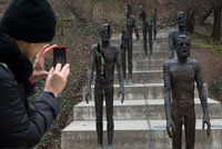 Monumento a los muertos del hambre situado a los pies del funicular que lleva hasta el mirador de Petrín.  Muro del Hambre Se trata de una pared que, atravesando el parque, se extiende casi desde el río Moldava, a la altura de la estación Ujezd donde se encuentra el funicular, hasta el Monasterio Strahov.  ¿Por qué tiene ese nombre? Ciertamente no devoraba a los transeuntes ni nada por el estilo... Este muro fue construido en tiempos de Carlos IV, entre 1360 y 1362, cuando una hambruna afectaba seriamente a la ciudad. El emperador decidió ampliar las fortificaciones defensivas al sur de Malá Strana, empleando especialmente a los más pobres y proporcionándoles a cambio comida para ellos y sus familias. La Colina Petrin se eleva hasta alcanzar los 327 metros al sur de Malá Strana. En otros tiempos proveía de las piedras necesarias para la construcción de casas y monumentos en la ciudad; actualmente, sus laderas forestadas y adornadas con jardines proporcionan un espacio muy agradable para pasear disfrutando de las mejores vistas sobre Praga y el río. El más reciente de sus jardines es un precioso rosedal que data de 1931, un espacio muy bonito para visitar en las estaciones más cálidas. 