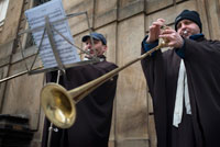 Dos músics vestits de cléricos i entonat melodies amb llargues trompetes promocionen un concert d'orgue a l'Església de Sant Francesc d'Assís. També coneguda com a església de Sant Francesc dels Creuats de l'Estrella Roja, aquesta església barroca, dedicada al primer màrtir catòlic incorporat a la litúrgia de Bohèmia, va ser construïda a mitjan segle XVII per l'arquitecte i pintor francès JB Mathey.