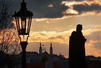 Estàtues al vespre al pont de Carles. Praga. El pont de Carles, és el monument més cèlebre de Praga, i comunica la Ciutat Vella i Malá Strana. Tot i que actualment és de vianants, en el seu temps podia donar pas a quatre carruatges en línia. Avui dia, moltes de les estàtues que alberga són còpies, ja que les originals es consercan al Lapidarium del Museu Nacional de Praga. Fins 1741, aquest pont era l 'únic que creuava el Moldava. Mesura 520 m de llarg i es va fer amb blocs de pedra sorrenca, reforçada, segons es creu, afegint ous al morter. El encàrrec Carles IV el 1357 per substituir el pont Judit, destruït per les inundacions i es deu a Peter Parler. La seva primera estàtua va ser la de Joan Nepomuceno, inspirada en la estatutari de Benini del pont Sant'Angelo de Roma, ja que Joan de Neponucemo va ser llançat del pont per ordre de Wenceslao IV a 1393. En 1648 els successos van destrossar part del pont i en 1890 una inundació va destruir tres ulls del pont.