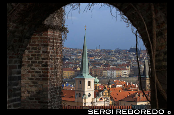 Vistas del Barrio de Mala Strana desde el Castillo de Praga. El barrio de Mala Strana se encuentra a los pies del Castillo de Praga y acaba en el río. Es la parte vieja de la ciudad y uno de los barrios más señoriales. Se nota en las calles, en los edificiosy en el ambiente. Las casas son de construcción antiguas, algunas muy recargadas, pero excelentemente conservadas, con colores vivos que desprenden fuerza. Todo está limpísimo y muy bien cuidado. Son calles pequeñitas, algunas en cuesta, con el castillo al final del todo. Muchas están asfaltadas con adoquines, lo que le da un aire aún más clásico. Una de las más bonitas es Nerudova, que es la que nos baja del castillohasta le centro del barrio. Al lado está la Iglesia de San NIcolás, digna de visitar. Merece la pena darse una vultecita larga por estas calles, que te remontan a tiempos pasados. Los restaurantes y bares también guardan ese estilo antiguo combinado con la modernidad de los tiempos que corren. Tomarse una cerveza en uno de ellos es un placer. Además, es uno de los mejores lugares para ocmer, pues sus restaurantes, la mayoría, son de muy buena calidad y no demasiado caros. En muchos sirven comida tradicional riquísima. Otra calle, esta más transitada y algo más moderna es Karmelitska, con decenas de comercios a los lados. Justo a uno de los lados del barrio está el monte petrín, que le da el toque verde y de naturaleza que le faltaba para ser un barrio casi perfecto. Desde aquí, al igual que desde el castillo, se puede ver el barrio desde las alturas, con las calles irregulares y decenas de terrazas con vistas increíbles a la ciudad. 