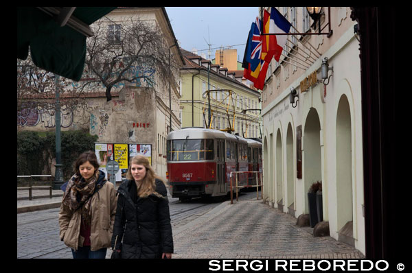 Un tramvia passa per davant de l'Hotel Roma a la part baixa del barri de Mala Strana . En l'antiguitat , Malá Strana va ser cridada Malé M ? Sto Praské ( La petita de ciutat de Praga ) . Malé M ? Sto Praské va ser creat en 1257 per una amalgama d'assentaments que s'estenien sota el Castell de Praga , constituint una única unitat administrativa . Això va ser sota el regnat de P ? Emysl Otakar II . El recent fundat nucli va obtenir el permís de ser una població Real i diversos privilegis més . Els residents eren majoritàriament artesans alemanys convidats pel Rei . Malgrat l' estatus Reial , el Rei no controlava la ciutat al complet . A mitjan segle la ciutat va canviar el seu nom a Malá Strana . Durant l'Edat Mitjana , Malá Strana va ser el centre més important de les ètnies alemanyes establertes a Praga . També va ser el lloc d'assentament de diversos palaus de la noblesa , en contraposició als pobles de la ribera dreta que , comparativament , eren més burgesos . Malá Strana (el significat literal és " Costat Petit " , encara que freqüentment el tradueix com " Poble Petit " , " Barri Petit " , o "Ciutat Petita ") és el nom original i actualment també l'oficial de la zona abans anomenada mensi m ? sto praské ( " El Districte Petit de Praga" ) , un dels districtes més antics i de major representació històrica a Praga . El nom d'aquest districte es deu a la seva posició a la riba esquerra del riu Moldava , a les lomadas que es troben als peus del Castell de Praga , en oposició als assentaments de major grandària que es trobaven a l'altre costat del riu. El famós novel · lista txec Jan Neruda va néixer i va viure gran part de la seva vida en aquest lloc , i diverses de les seves obres tracten sobre Malá Strana . El carrer Nerudova porta el seu nobre en honor a ell . Entre altres atraccions de la ciutat de Praga , la torre d'observació de Pet ? Índex es troba a Malá Strana . També en aquesta zona està la famosa imatge del Nen Jesús de Praga , a l'interior de l'església de la Mare de Déu Victoriosa . La devoció de milions de catòlics ha fet que aquesta església sigui un important punt d'interès a la ciutat.