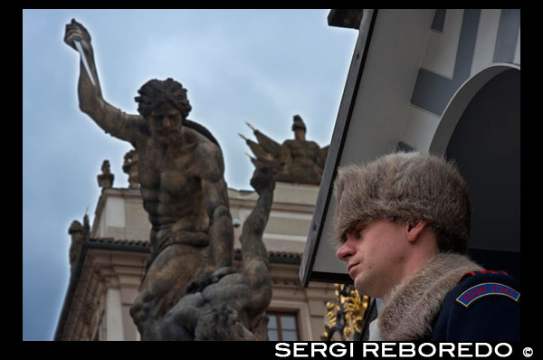 Uno de los guardias que custodia la puerta principal de acceso al Castillo de Praga.  El castillo consta de multitud de edificios, palacios, salas, exposiciones, iglesias, y por supuesto, el callejón dorado y la catedral. Entrar al recinto y andar por los patios es gratis, por lo que se puede subir y visitar sin pagar. Además, se puede entrar a la Catedral gratis (pero sólo entrar a los primeros metros; para verla entera hay que pagar).; al Callejón dorado también se puede entrar gratis a partir de las 17. En resumen, hay mucho que ver.. Hay al menos tres puntos de información donde comprar los tickets en los patios 2 y 3 del castillo; también se pueden comprar en la Galería de Arte, en el Palacio, en el callejón dorado y en el palacio Lobkowicz por lo que quizá conviene dar una vuelta a ver si hay alguna con menos gente... También se pueden comprar online. Una vez hecha la cola (que imaginamos que en verano puede ser infernal) hay que elegir qué se quiere ver. Cada "cosa" tiene un número del I al X. Hay varias opciones, dos de ellas agrupan la entrada a varias de las visitas obligadas, mientras que el resto son entradas "individuales" (a la sala permanente de exposiciones, a la torre de la Catedral, a la galeria de pintura, etc). Las dos opciones que agrupan entradas son: Visita corta: incluye la visita al Antiguo Palacio Real, a la Basílica de San Jorge, al Callejón Dorado, y a la Catedral de San Vito. En 2012 cuesta 250 CZK (unos 10€ al cambio actual). Puede tardarse fácilmente 4 horas en ver estas 4 cosas, quizá más yendo despacio para apreciar bien todo, o si hay mucha gente. Visita larga: incluye lo anterior más: La exposición permantente ·La historia del Castillo de Praga), el convento de San Jorge, la Galería de Pintura, la Torre de la pólvora (no confundir con la que está en el centro, en Nám?stí Republiky) y el Palacio Rosenmberg). Son 350 CZK. Los tickets son válidos dos días consecutivos, lo cual puede resultar útil si se hace la visita despacio (máxime en invierno, cuando las visitas son de 9 a 16 en lugar de terminar a las 18) Además de lo anterior, se puede visitar la torre sur de la Catedral de San Vito; esta entrada se compra en la propia torre (creemos que la gestiona la iglesia y no el Castillo, por lo que el precio no aparece en la web oficial) 