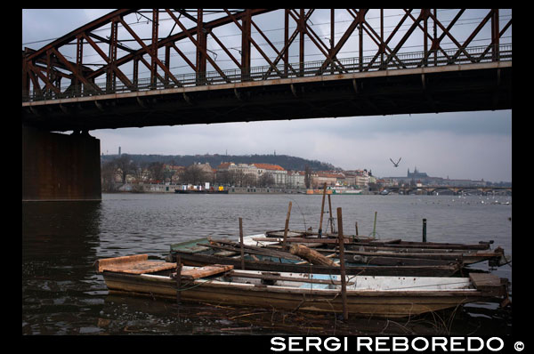 Puente sobre el Rio Moldava en el centro de Praga.  El Moldava, el río más grande de la República Checa, divide a la capital checa en dos partes.  Un bonito paseo que se puede hacer por Praga es recorrer la vera del río al atardecer, pudiendo ver el Castillo de Praga, el Puente de Carlos, y muchos otros lugares destacados.  Si seguimos dirección sur al lado del río, llegaremos a la denominada zona nueva. El aspecto es el mismo que en la zona vieja, con el mismo estilo arquitectónico y colorido de fachadas, aunque las calles son más anchas y hay menos edificios históricos. Uno de los lugares más llamativos es la Casa Danzante, un extraño edificio de estilo descontructivista que llama mucho la atención. Es muy simpático ver como en medio de tantas construcciones clásicas y regias se encuentra esta casa danzante, con un aspecto hiperfuturista, pero que no desentona para nada con el entorno. Un buen ejemplo de como hacer un bonito edificio hoy en día.