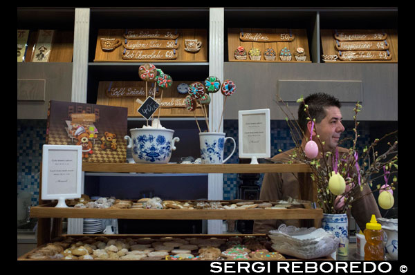 Tienda especializada en galletas de jengibre. Incluso realiza talleres para que los niños las elaboren.   Para preparar galletas de jengibre necesitamos: 350g de harina, 130g de azúcar en polvo, 20g de mantequilla, dos huevos, tres cucharadas de miel, media cucharadita de bicarbonato de sodio, una cucharadita de la mezcla de especias para pan de jengibre, que contiene cilantro, badián, anís, canela, clavo de especia, hinojo, pimienta de Jamaica y vainilla, y un huevo para untar las galletas. Mezclamos los huevos con el azúcar, la miel y las especias y añadimos la mantequilla derretida. Poco a poco vamos añadiendo la harina con el bicarbonato de sodio hasta obtener una masa ni espesa ni demasiado blanda. Dejamos reposar la masa en un lugar frío (pero no en el refrigerador) hasta el día siguiente. Estiramos la masa con el rodillo hasta obtener medio centímetro de grosor. Cortamos las galletas con moldes de diferentes formas y tamaños, con motivos navideños. Colocamos las galletas sobre la bandeja cubierta de papel encerado dejando bastante espacio entre una y otra. Metemos en el horno precalentado y horneamos durante unos 8 o 10 minutos. Dos minutos antes de sacar la bandeja del horno, untamos las galletas con el huevo batido. Cuando estén frías, las adornamos con glaseado preparado de una clara de huevo y 100g de azúcar en polvo. Quien desea tener las galletas un poco más oscuras, puede añadir a la masa una cucharadita de cacao.  “Los artesanos jengibreros agrupados en el gremio tenían la obligación de fabricar pan de jengibre en la región donde habían aprendido el oficio. Para poder ingresar en el gremio tenían que estar casados y pagar una suma de dinero bastante alta. Los que no tenían esposa o recursos suficientes, muchas veces se casaban con una viuda de un jengibrero para alcanzar la membresía y el prestigio que suponía”. Más tarde, la situación cambió. En el siglo XVIII, el pan de jengibre dejó de ser una delicia de lujo y se difundió entre todas las clases sociales. A principios del siglo XIX comenzó la producción masiva de este alimento. Fue la época de oro del pan de jengibre. Pero poco a poco, su fabricación cedía al progresivo desarrollo de pastelería y confitería industrial. Y a principios del siglo XX ya quedaban realmente pocos los que se dedicaban a este oficio. Pero por suerte la tradición del pan de jengibre nunca ha desaparecido del todo. Ni tampoco las leyendas que se contaban de él. Antonín Novotný recuerda una de ellas. “La leyenda cuenta que cuando en la familia de un artesano jengibrero nacía una niña, éste bajaba ese mismo día a su taller y preparaba la masa de pan de jengibre. La colocaba en un saco de tela que ataba a la viga del techo de su casa. Años después, cuando la niña se iba a casar, sacaba la masa, la volvía a trabajar y hacía de ella pasteles de boda”. Muy bonito. Antes de terminar, creo que también deberíamos mencionar la decoración del pan de jengibre. Es verdad. Mucha gente lo recibe como regalo y en vez de comérselo, lo cuelga en la pared como un cuadro o lo coloca en algún lugar visible de su casa guardándolo como recuerdo, porque les da pena comerse algo tan bonito. Pero según yo tengo entendido este dulce antes no se decoraba... La tradición de decorar el pan de jengibre comenzó a fines del siglo XIX. Entonces se pegaban sobre él imágenes impresas de caballos, soldados, santos, etc. Algunos panaderos solían añadirle flores, espejitos y cintas de colores para darles más brillo. Hoy en día, se suelen decorar con glaseado preparado de claras de huevo y azúcar. Algunos prefieren diseños blancos, que recuerdan encajes o escarcha. Otros le añaden colorantes al glaseado. Al igual que los métodos de decoración, cambiaban los motivos del pan de jengibre. En el siglo XVI prevalecían corazones, en el XVII eran muy populares los retratos de reyes y santos. En el siglo XVIII, los motivos preferidos eran palomas, caballos y bebés y, más tarde, durante la revolución industrial, eran populares trenes, pistolas y relojes. Y hoy día, de todo un poco, afirma Antonín Novotný. “La cantidad y las formas de pan de jengibre que producimos varía durante el año. El mayor consumo se registra en Navidades, la Semana Santa, el día de San Nicolás y el día de San Valentín. Para Navidades preparamos sobre todo belenes, casitas nevadas y campanas; para las Pascuas, conejitos, pollos y huevos; para San Nicolás, figuras de ángeles y diablos; y para San Valentín, corazones”. 